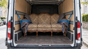 Alte Couch steht mit Schutzdecken und Gurten gesichert im Möbeltaxi